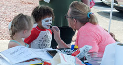 young girl getting her face painted like a Dalmatian dog