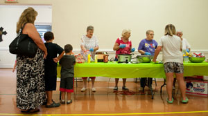 people waiting in line to get hot dogs at tables in gym area