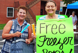 sandwich board sign and two people handing out free freezer pops